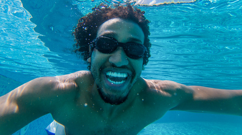 man swimming underwater in pool