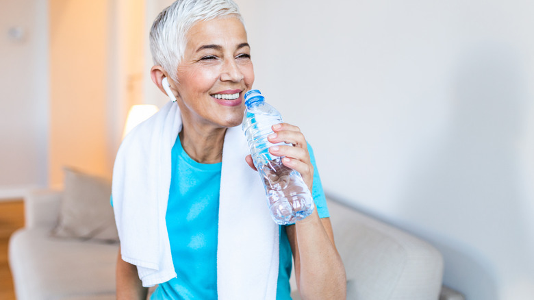 Mature woman with sweat towel drinking water