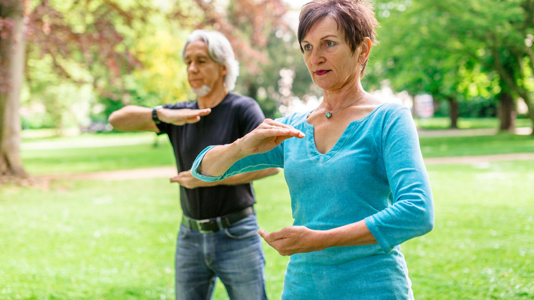 middle aged woman doing tai chi with husband