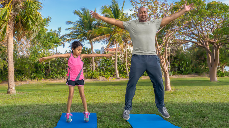 man doing jumping jacks with daughter