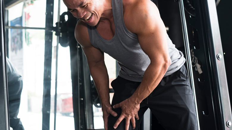 man holding knee in gym