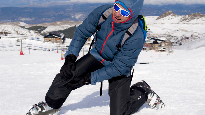 man holding knee in snow