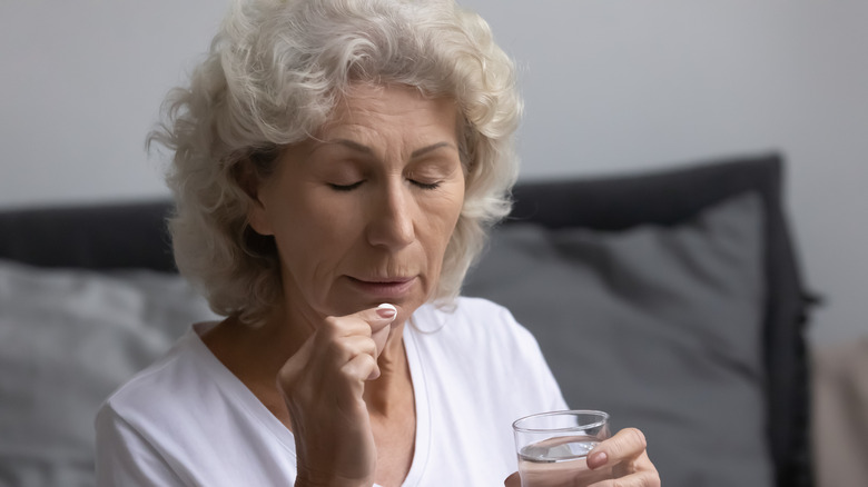 Woman taking pill in bed