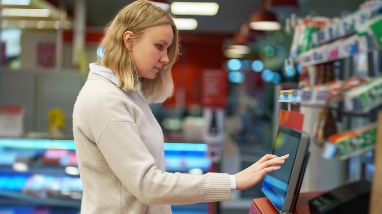 woman using self checkout at supermarket