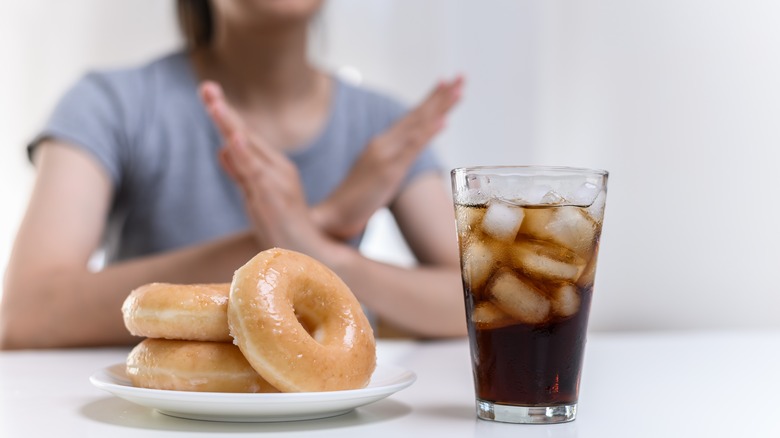 Woman rejecting donuts and soda