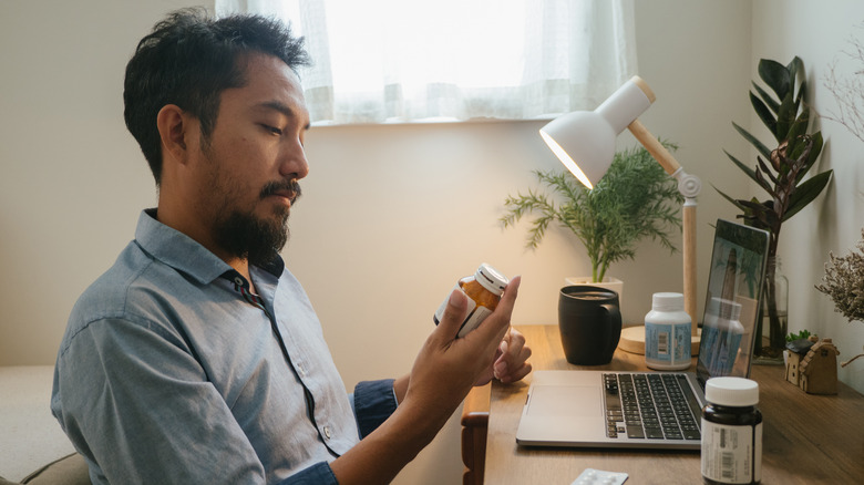 Man holding medications during telehealth appointment