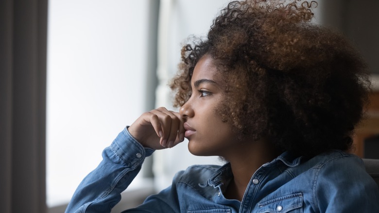 Teen girl looking thoughtfully out window