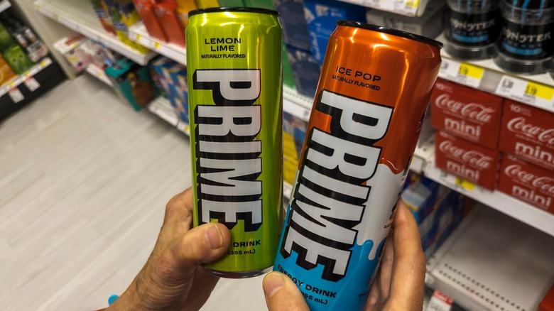 Hands holding two Prime Energy drinks