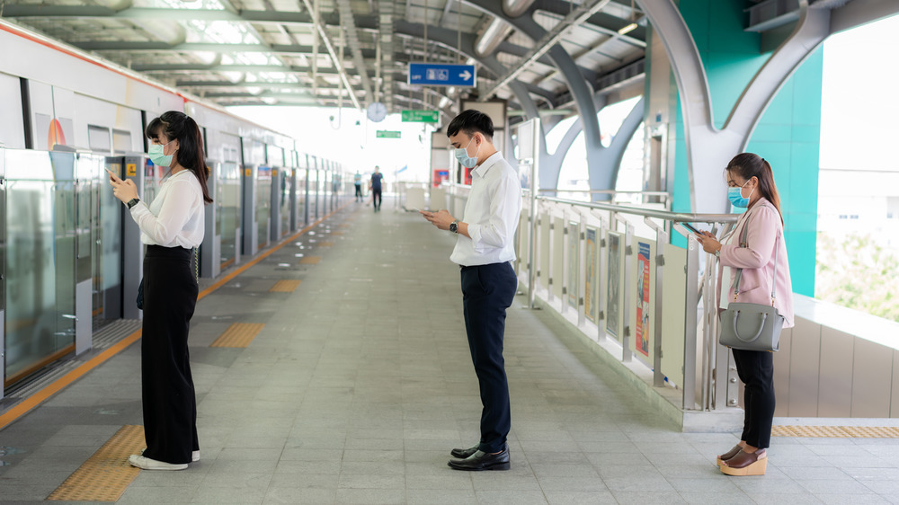 People waiting to board a train while social distancing 