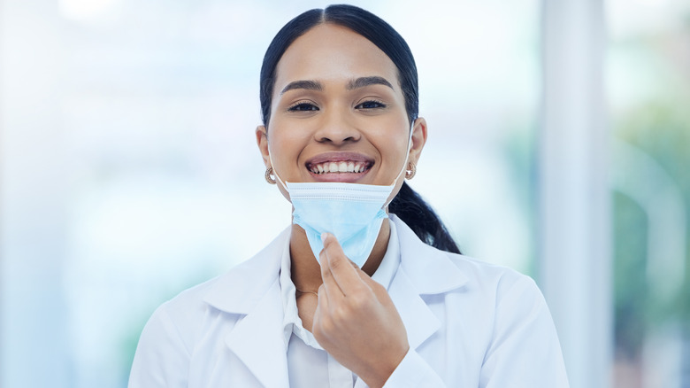 Smiling doctor pulling down facemask
