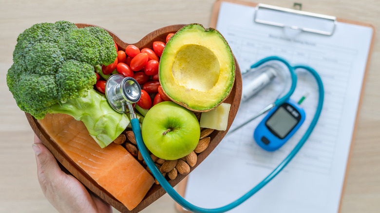 heart shape bowl with healthy food and stethscope