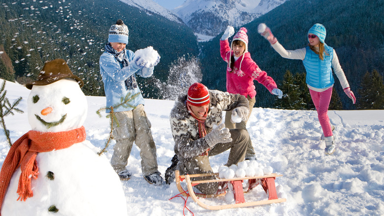 Family throwing snowballs with snowman