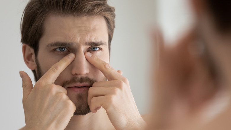 Worried middle-age man looking at eyes in mirror