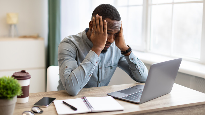 man has headache while working on laptop