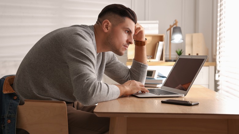 man with poor posture hunched over laptop