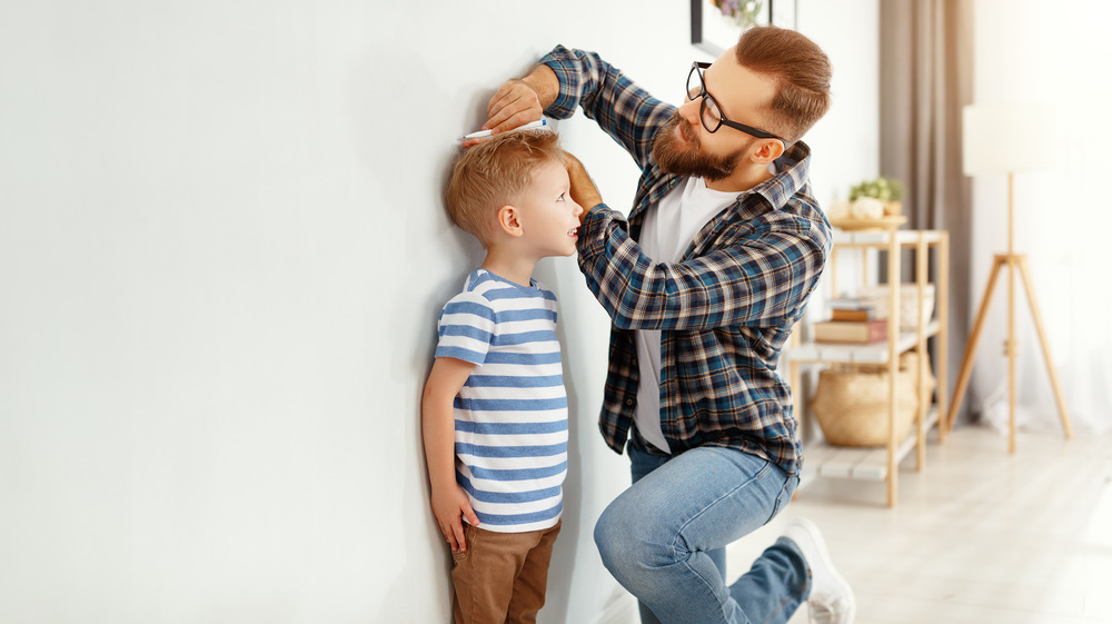 A father measuring the height of his son 