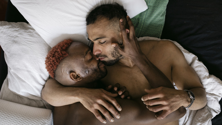 two men embracing in bed