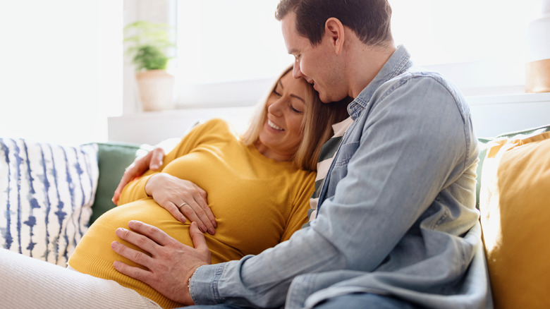 Pregnant women and man sitting together on couch