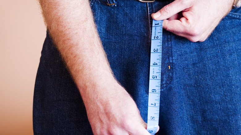 Man holding measuring tape to crotch