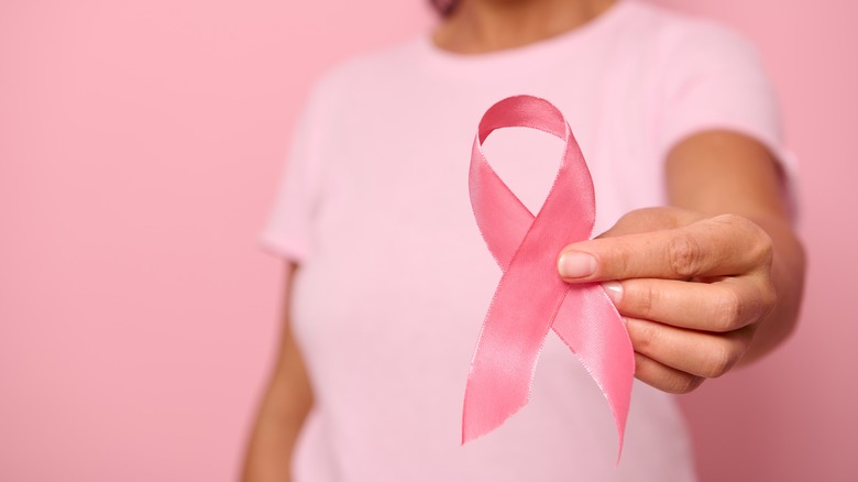 A woman holds a breast cancer awareness ribbon