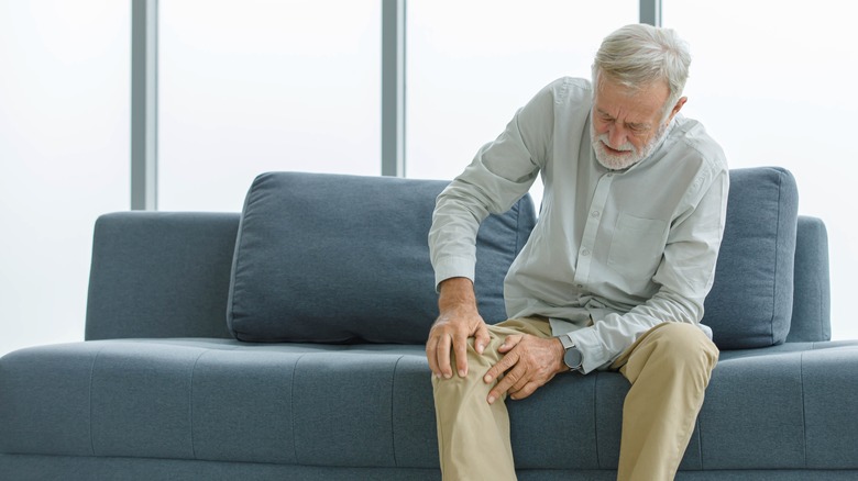 A senior man holds his knee in pain