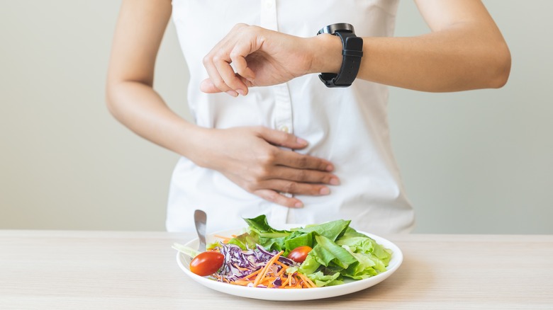 woman looking at her watch in front of a salad