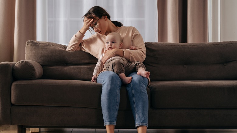 Stressed woman and baby on couch