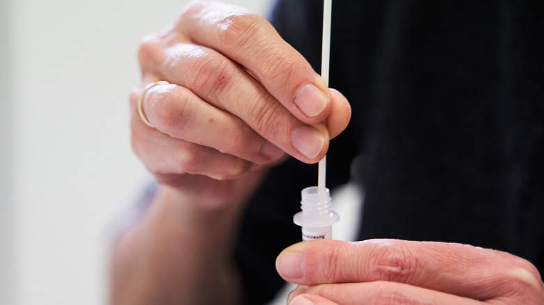 Hand inserting self-swab into vial