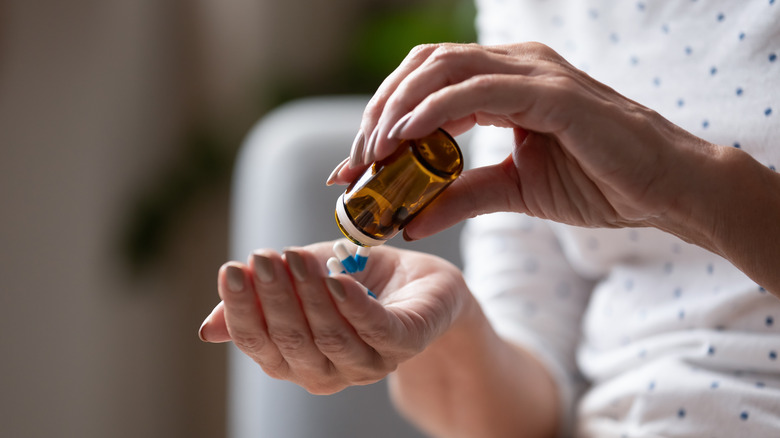 woman's hands emptying pills from prescription bottle