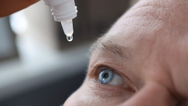 man using eye drops