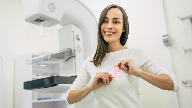 woman in front of mammography holding a breast cancer ribbon 