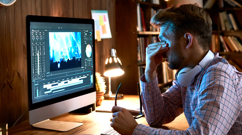 Man at computer rubbing eyes