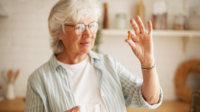 Older woman holding an omega-3 pill