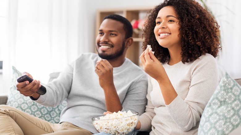 Smiling couple eating popcorn