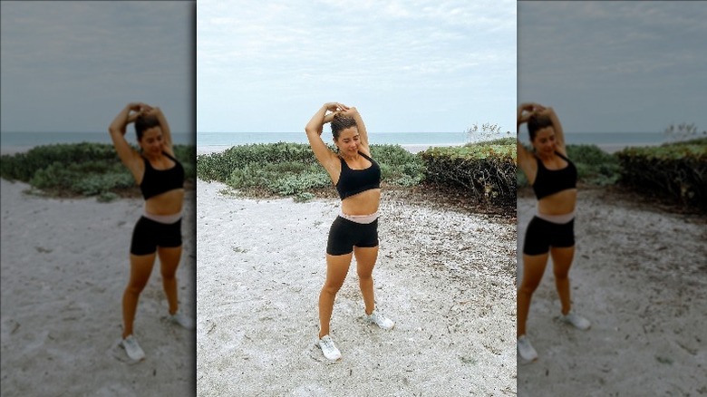 Fitness influencer Ali Kay stretches on the beach