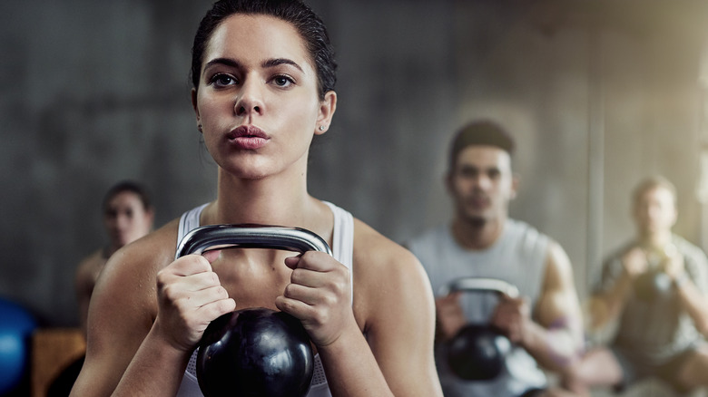 Young woman lifting weights at gym