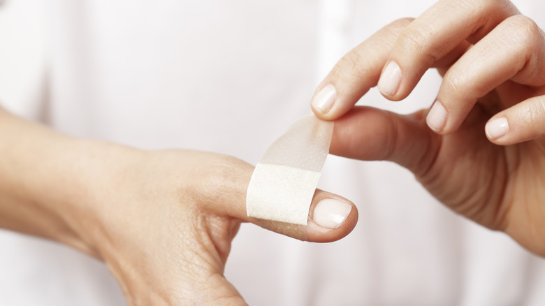 hand applying a bandaid to paper cut