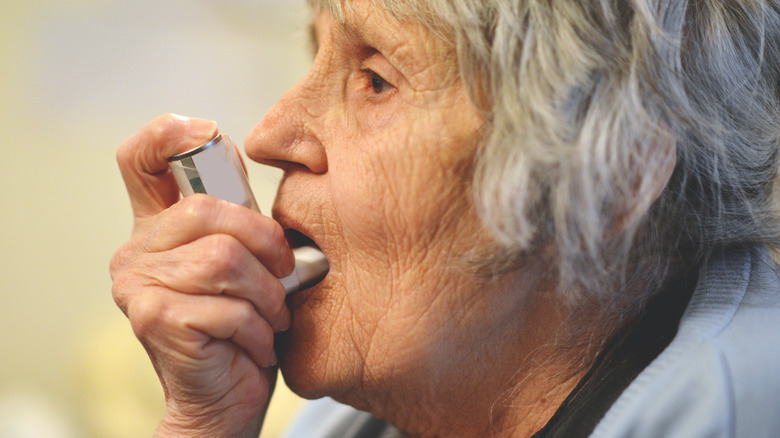 older woman using fluticasone inhaler