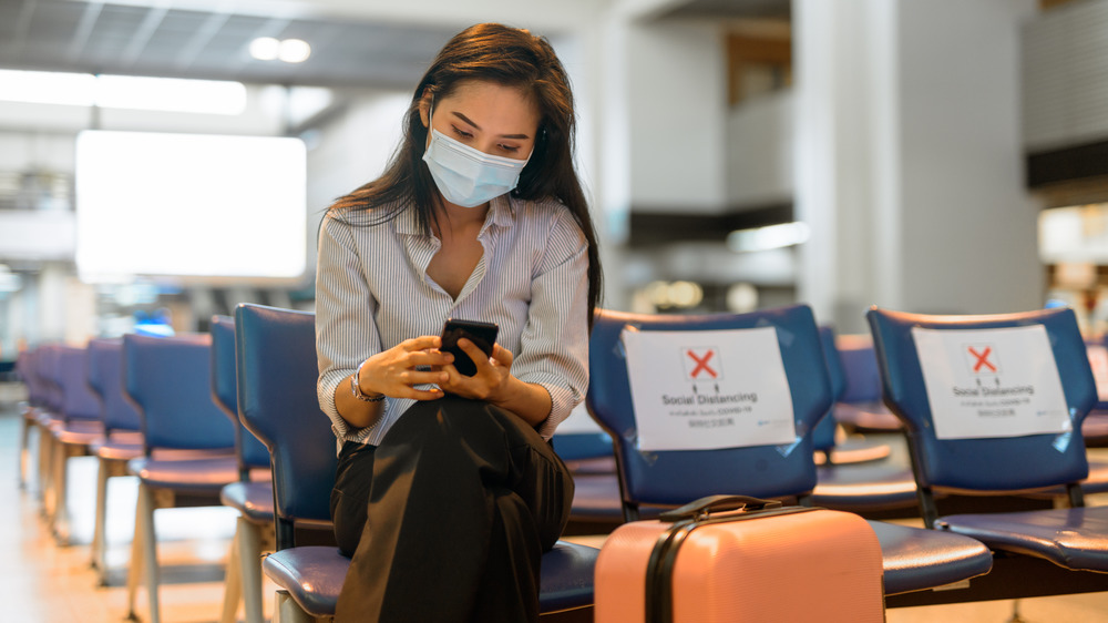 Stock photo of young woman traveler social distancing at airport