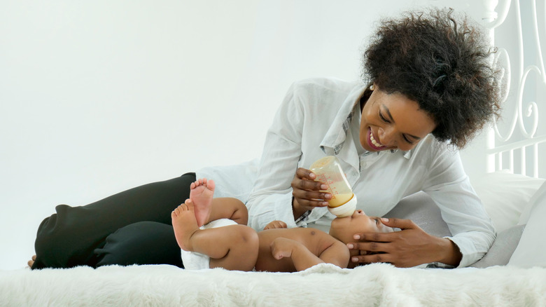 Mother feeding her baby a bottle in bed