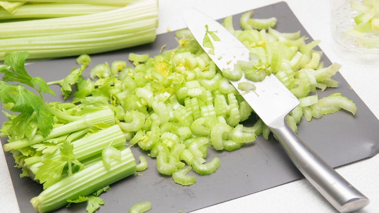 Chopped celery on a cutting board with knife