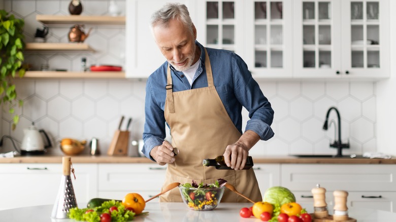 man adding healthy oil to salad