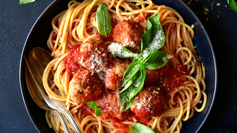 spaghetti and meatballs in black bowl