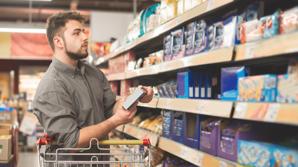 Man looking at product in grocery aisle