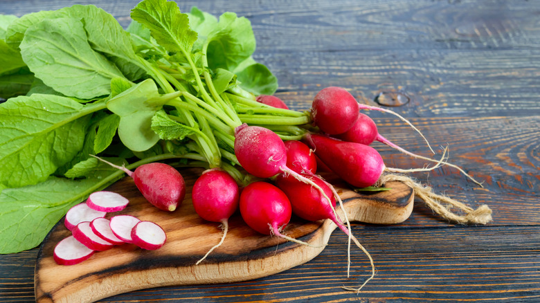 Radishes and radish slices on a wooden board