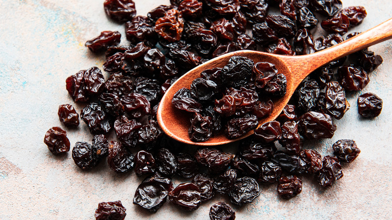 A pile of raisins and a wooden spoon