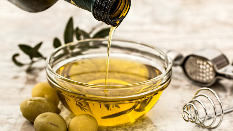 closeup of olive oil pouring in bowl