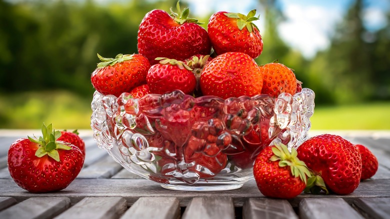 A transparent vase with strawberries outdoors
