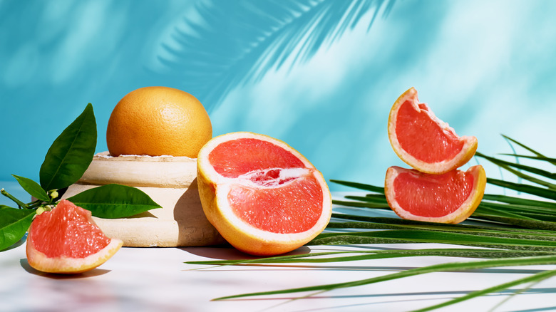 Pink grapefruit and three grapefruit slices by palm leaves