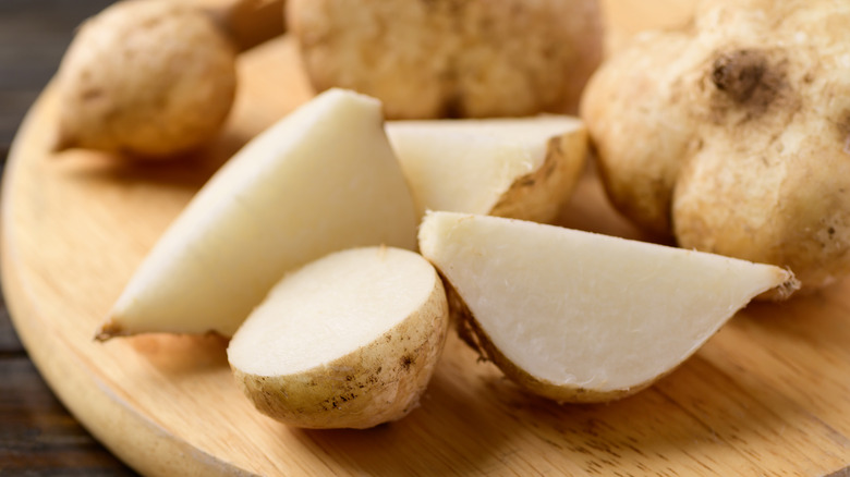 Close up of sliced jicama with whole jicamas in the background